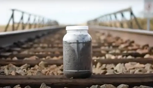 jar of soil on railroad tracks.