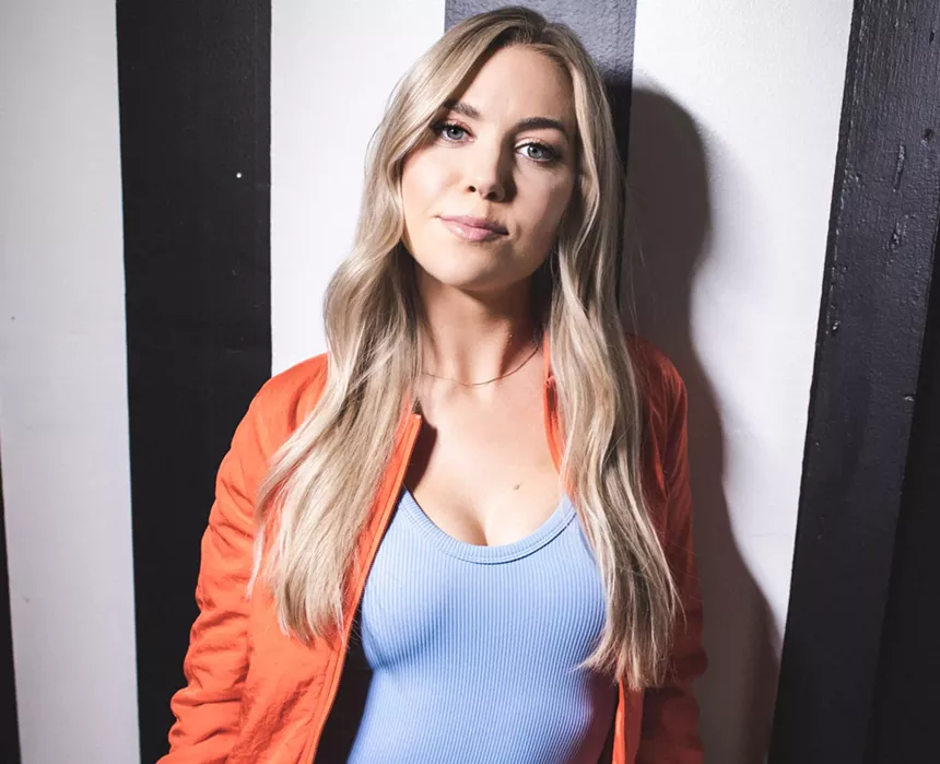 blonde woman in orange jacket and blue tank top