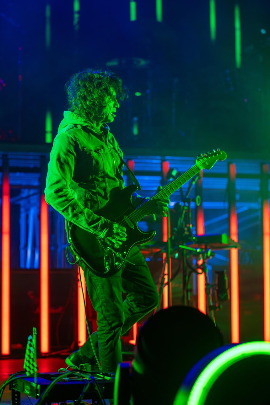 man in a mask playing guitar in green lights