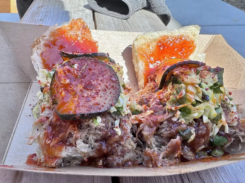 Two BBQ pulled pork sliders topped with mustard slaw and Korean pickles