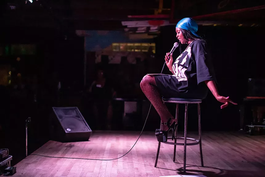 woman sitting on a stool holding a microphone