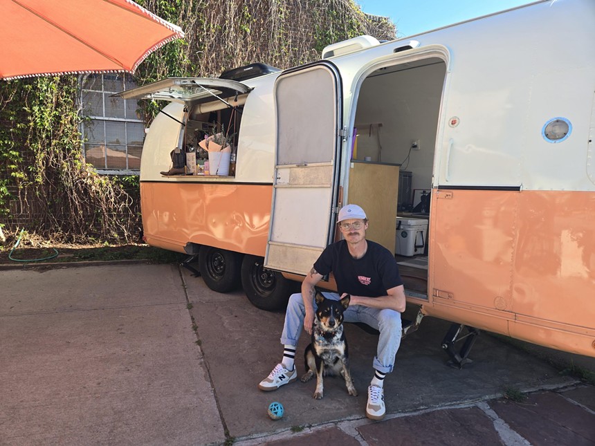 a man and a dog sitting in front of an orange and tan van