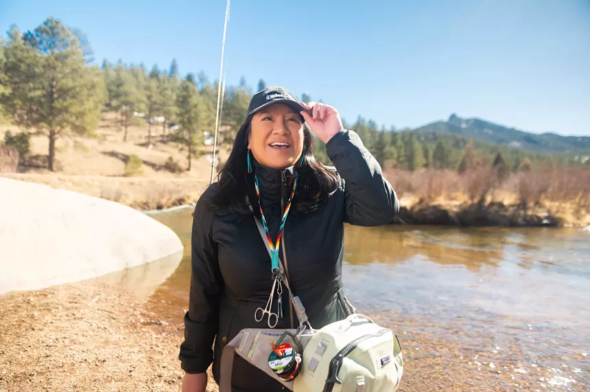 Indigenous guide Erica Nelson posed in fly fishing gear along a river