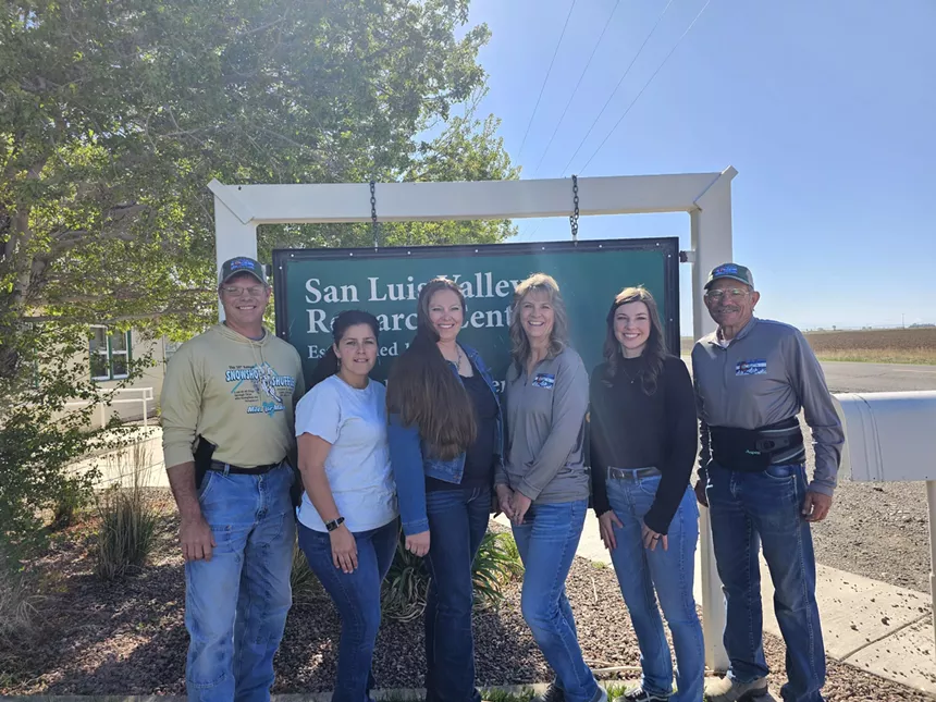 a group of people posing in front of a sign