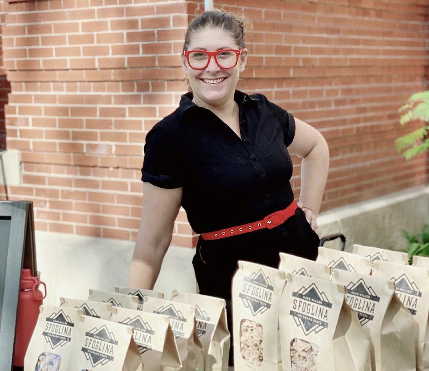 woman posing behind bags of pasta