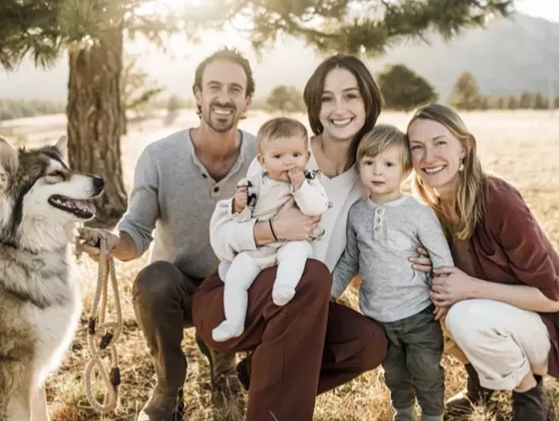 couple posing outside with three kids and a dog