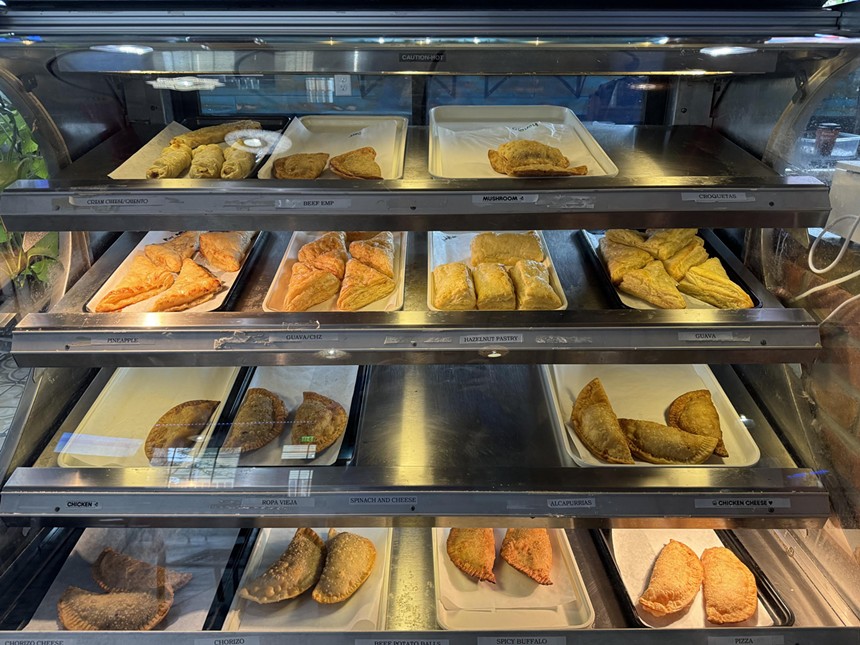a bakery case filled with empanadas and pastries.