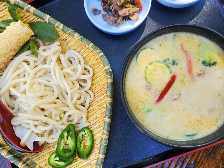 noodles on a tray next to a bowl of light colored broth