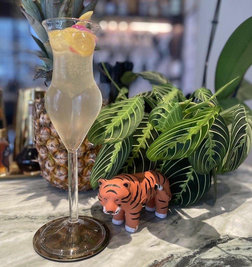 a cocktail next to a tiger figurine and a plant