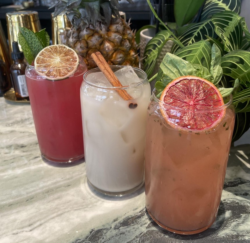 three cocktails in front of a pineapple and a plant
