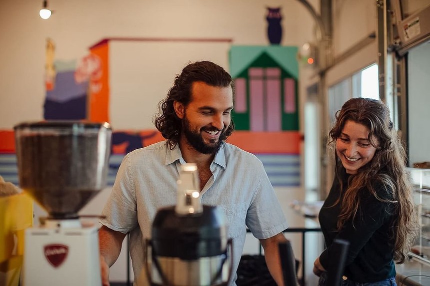 a man and a woman standing in front of coffee brewing equipment