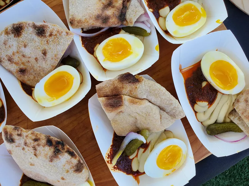 small plates of hummus, pita and a soft-cooked egg