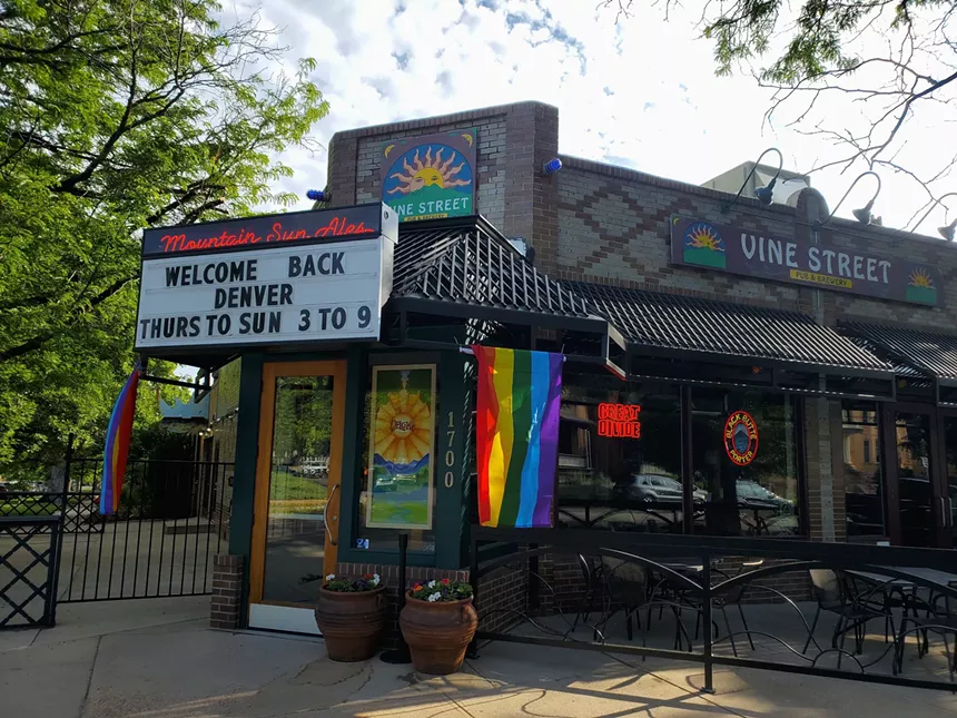 front of a building with rainbow flags hanging from a sign
