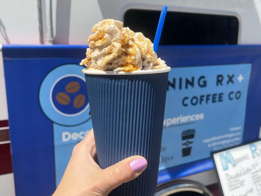 hand holding a latte in a blue cup
