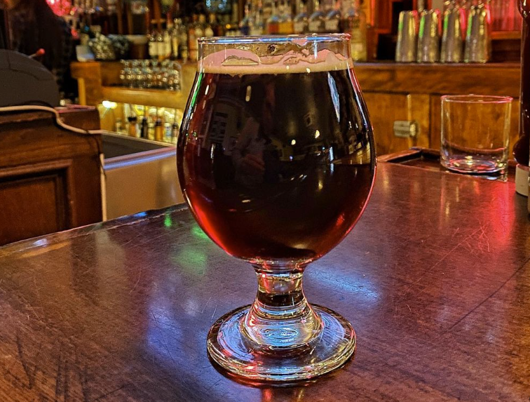 Beer in a snifter on a bar top.