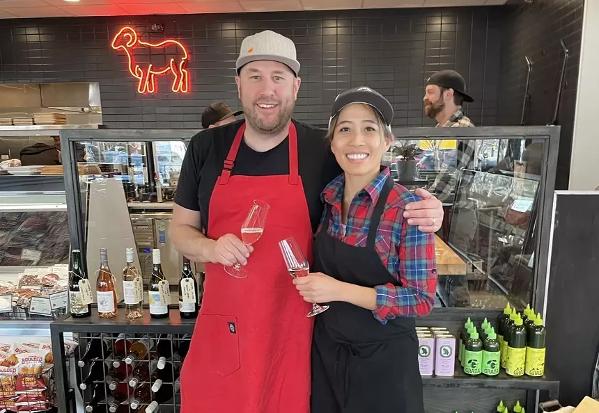 a man in a red apron posing with a woman in a black apron