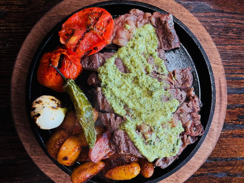 ribeye asada with a green sauce and roasted tomatoes