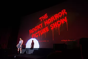 A woman dances on stage in front of the title card of The Rocky Horror Picture Show.