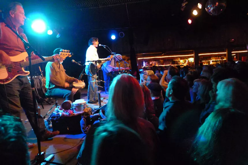 band on stage in dark bar.