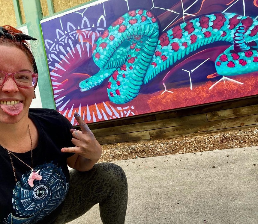 woman posing next to a mural