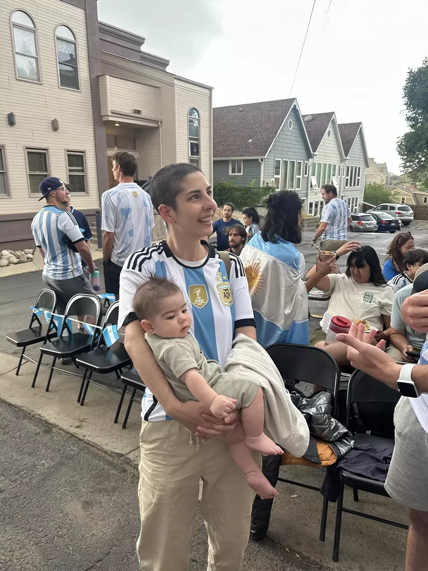 woman in a blue and white jersey holding a baby