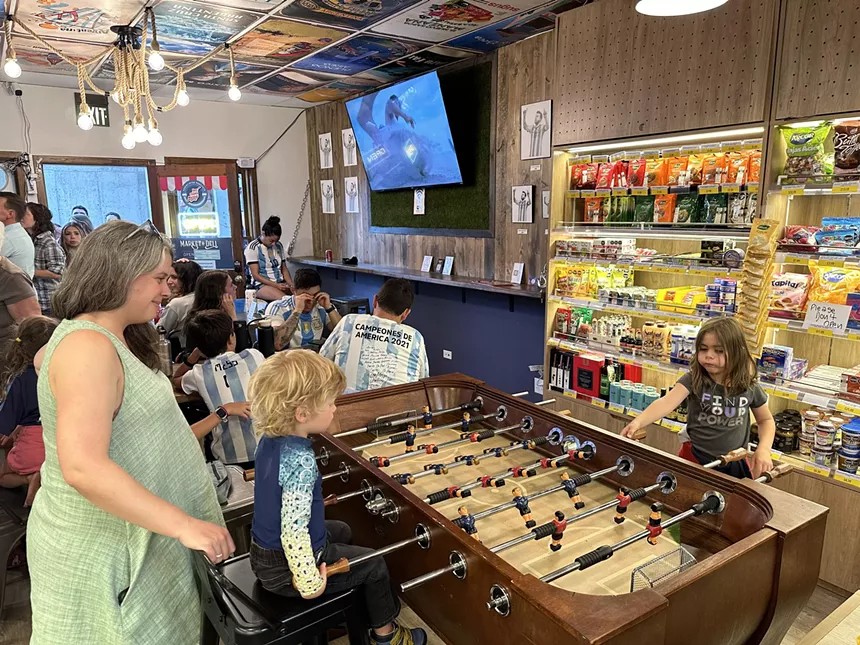 woman and two children playing foosball