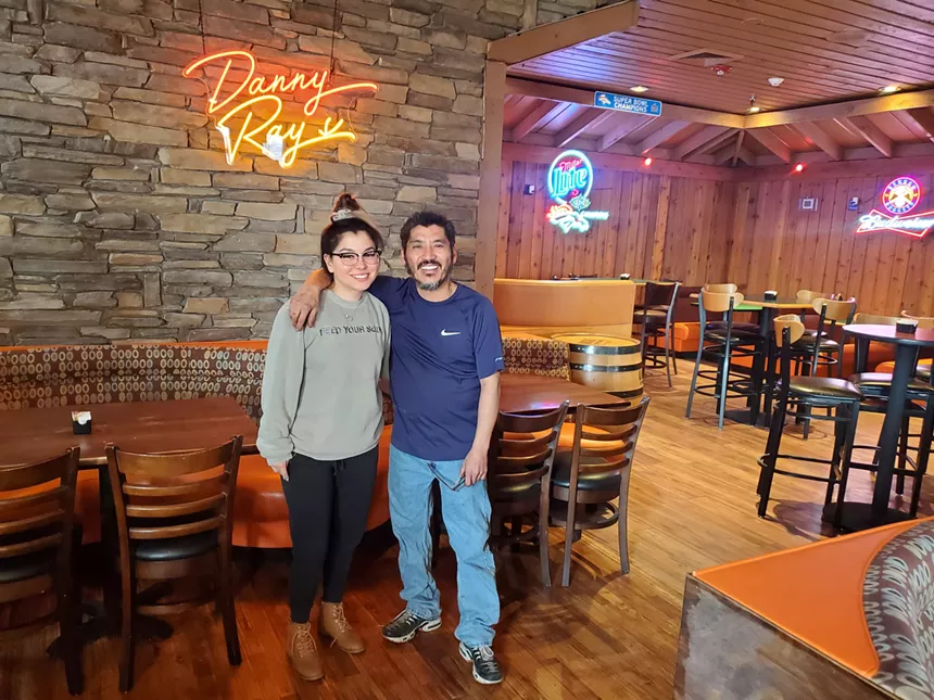 man and woman posing in front of a neon sign that says "danny ray's"