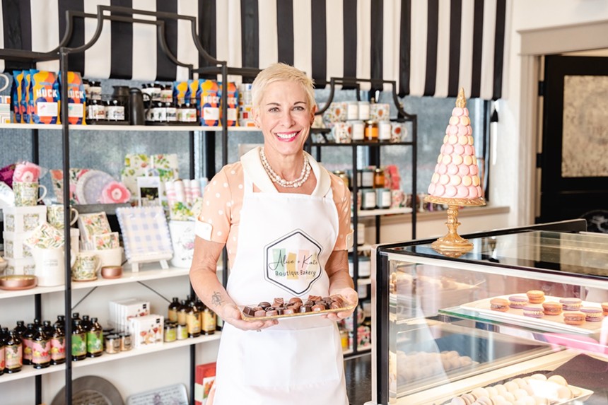 woman in a white apron holding a tray of chocolates