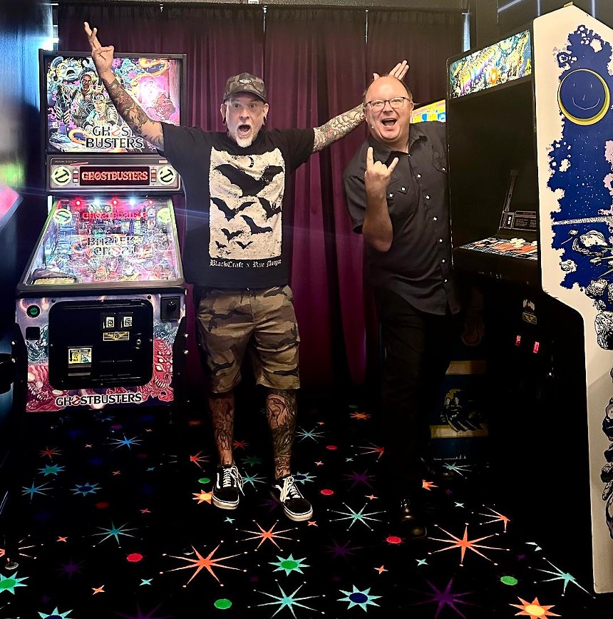 two men standing neat to arcade games