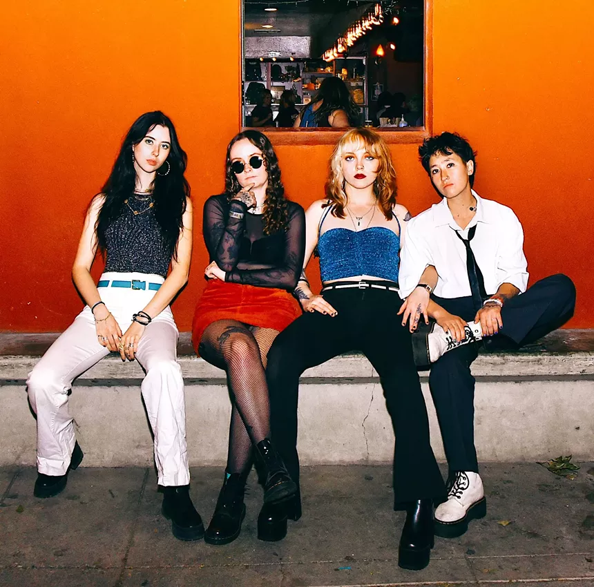 four femme musicians sitting in an orange room