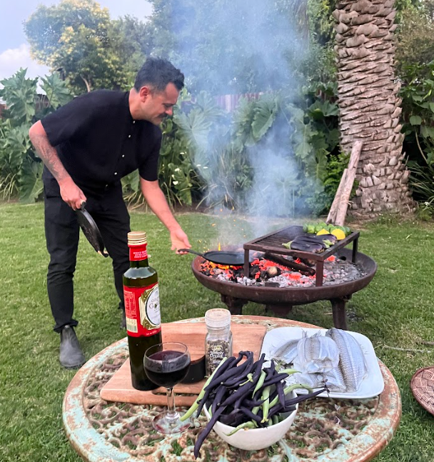 a man in ab lack shirt cooking over live fire