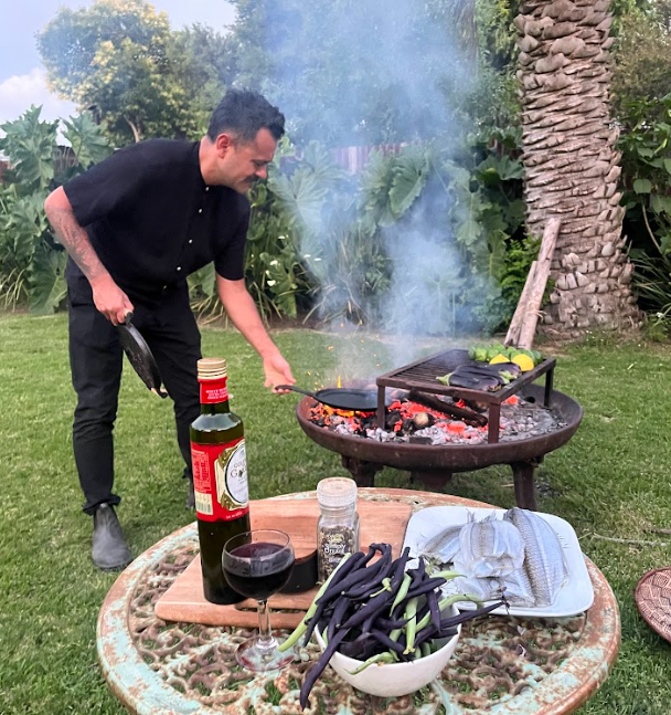 a man in  ab lack shirt cooking over live fire