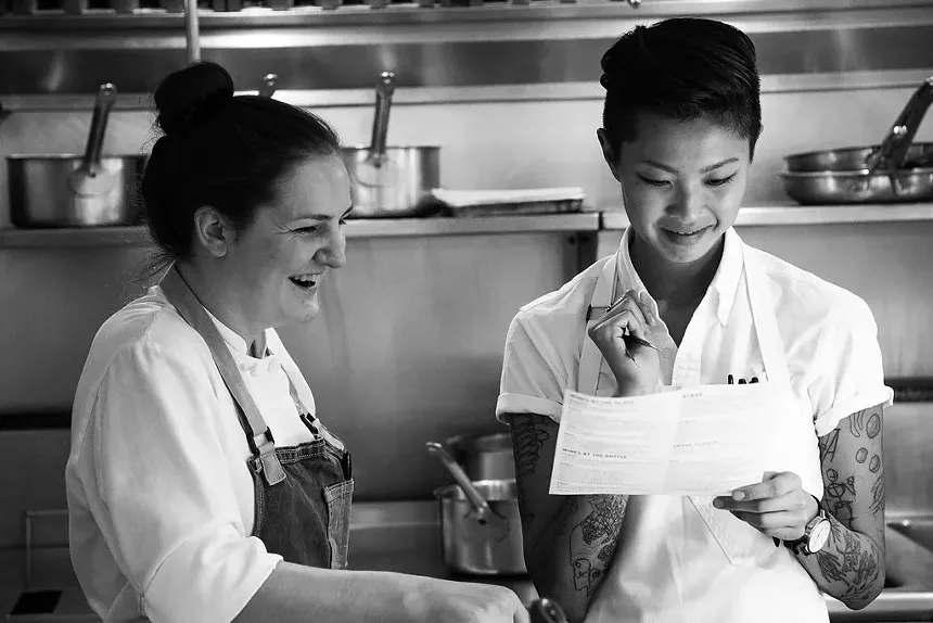 black and white photo of two women in aprons in a kitchen