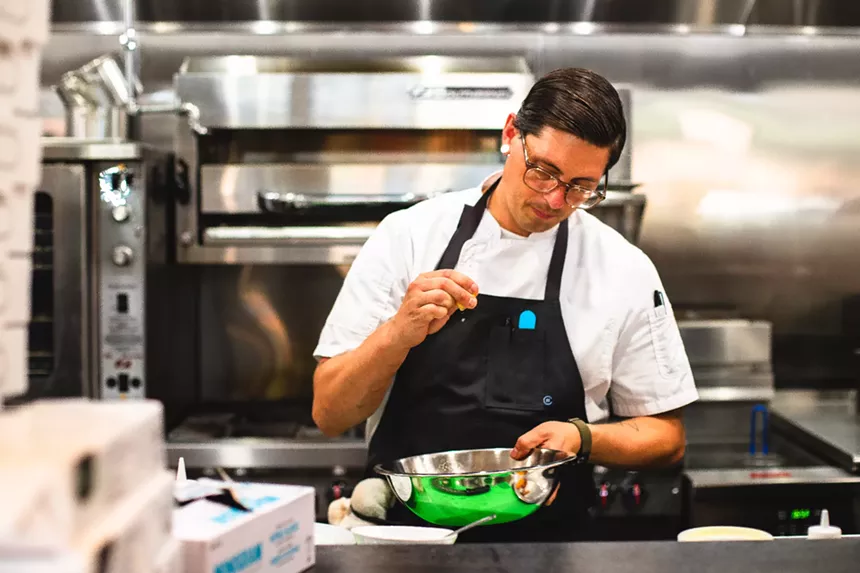 man in an apron holding a large metal bowl