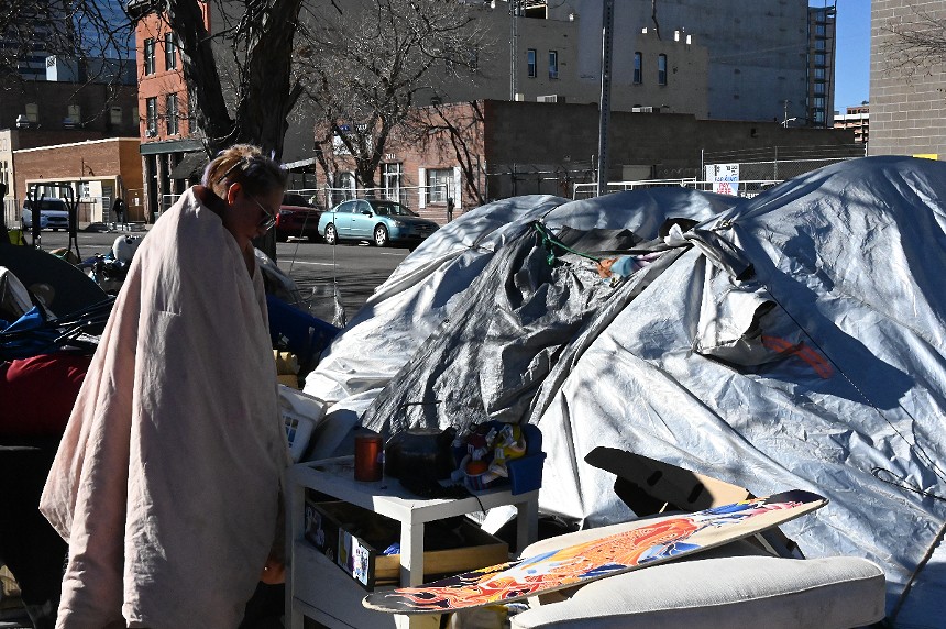 A homeless resident stands outside her tent.