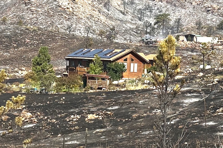 A house sits on charred land.