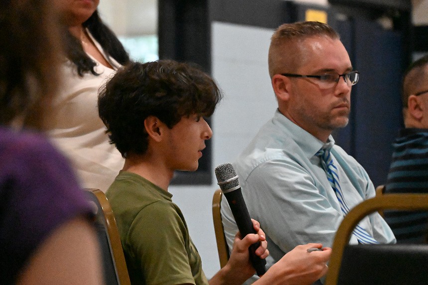 A boy talks with a microphone during a town hall