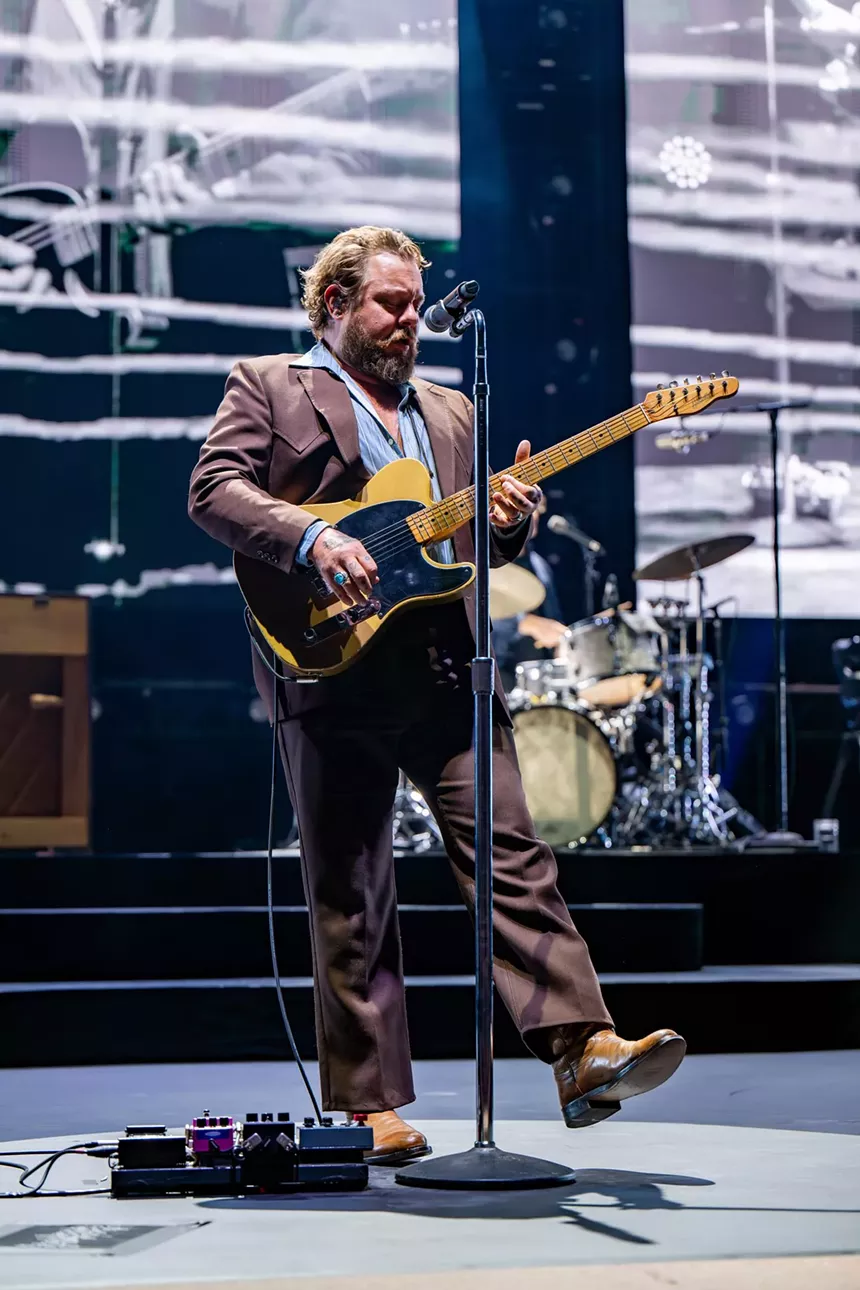 Nathaniel Rateliff in brown jacket playing guitar
