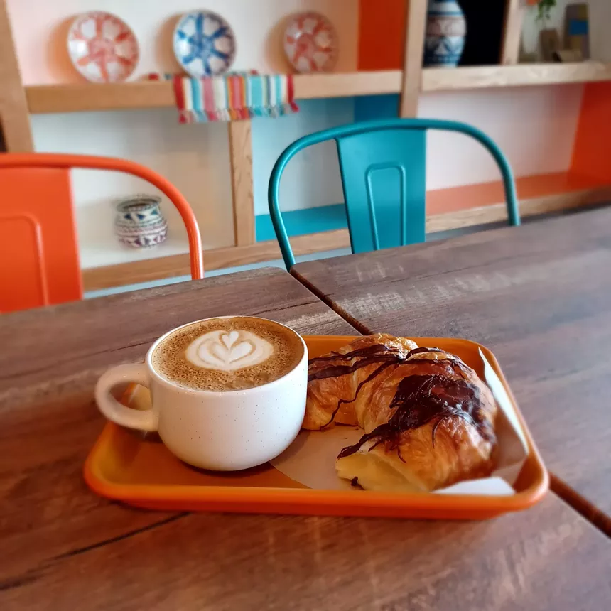 cup of coffee and a chocolate croissant on a tray