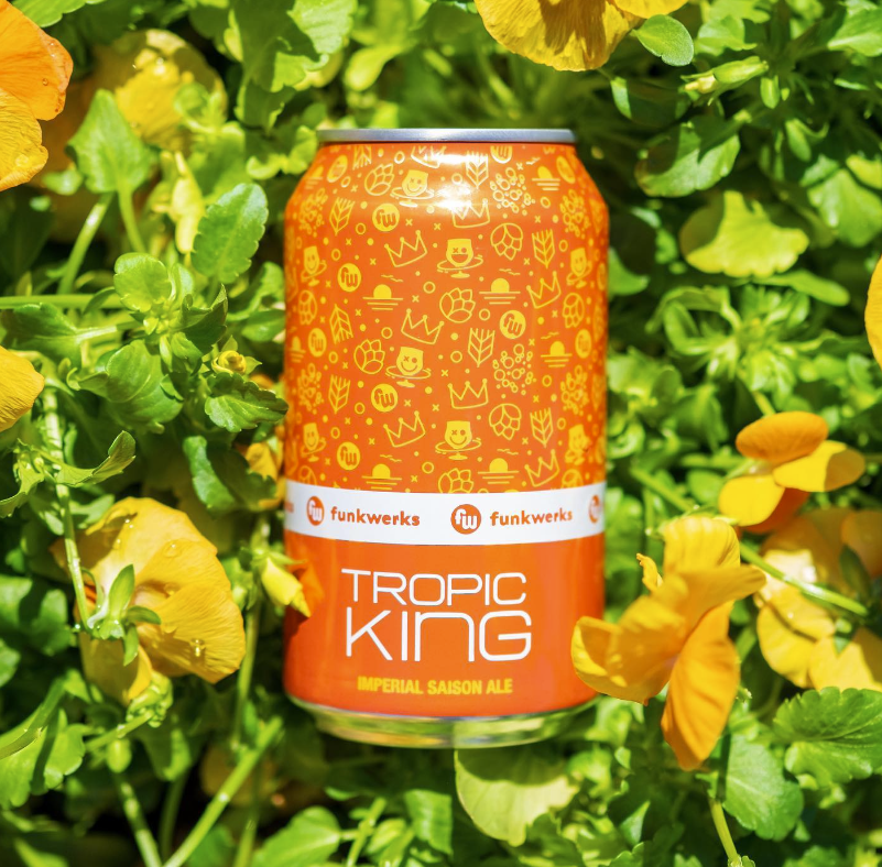 Orange can of beer outside in flowers.