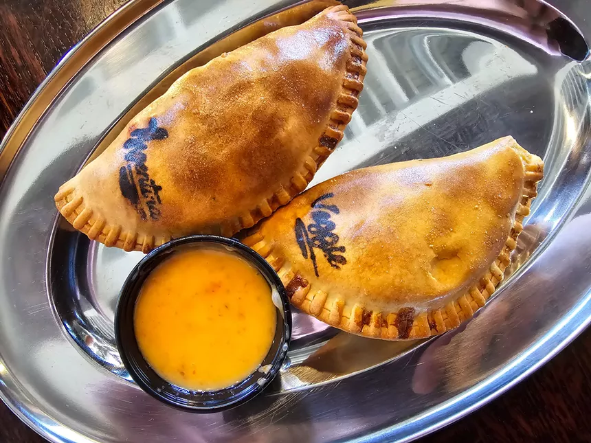 two empanadas on a silver plate