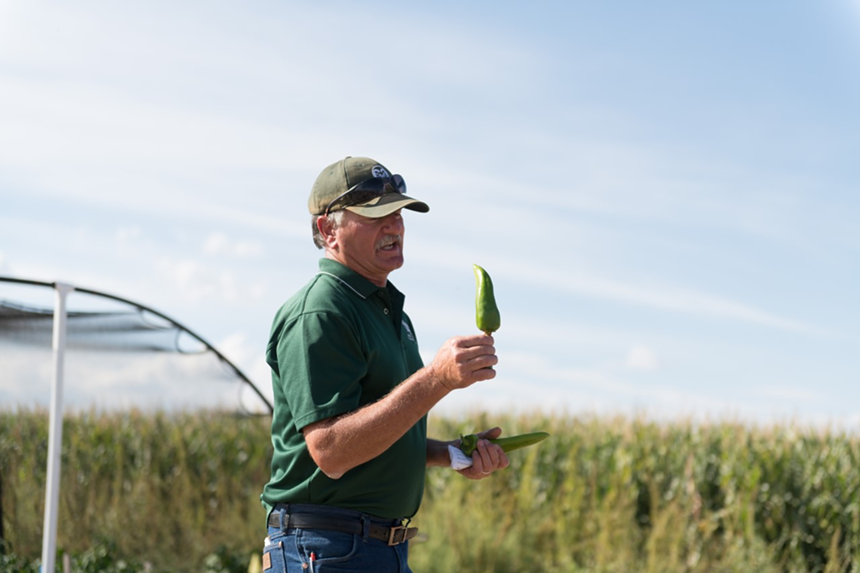 man in field holding pepper