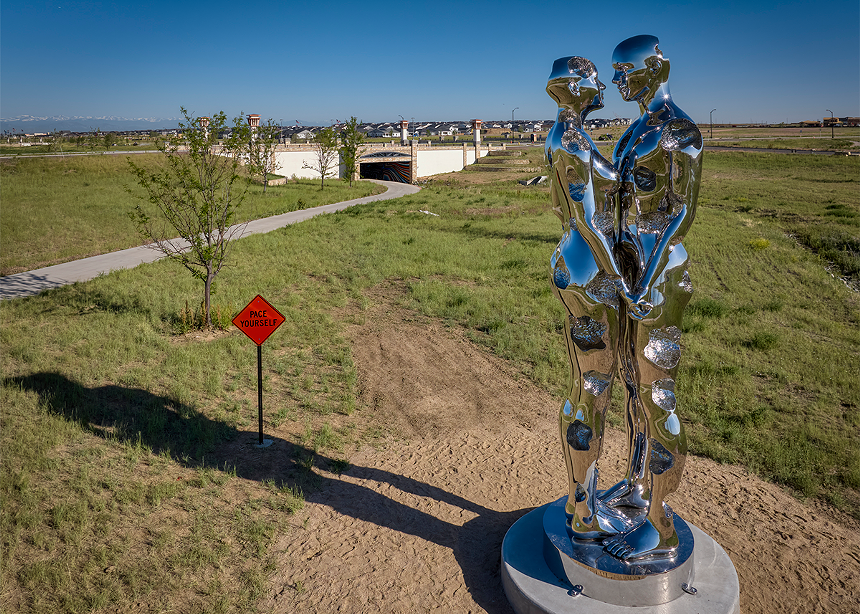 giant silver sculpture of two people hugging in a park