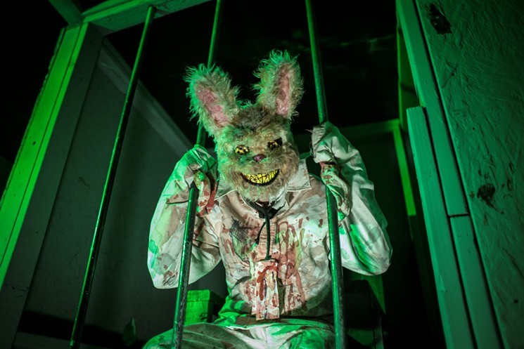 An actor in a creepy rabbit costume set behind bars at Haunted Field of Screams