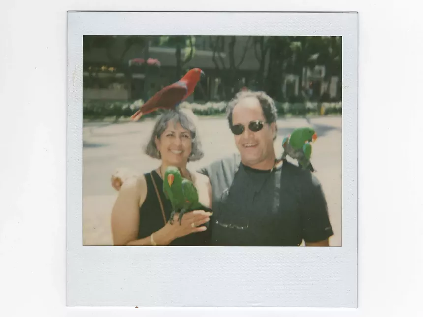 man and woman posing with parrots