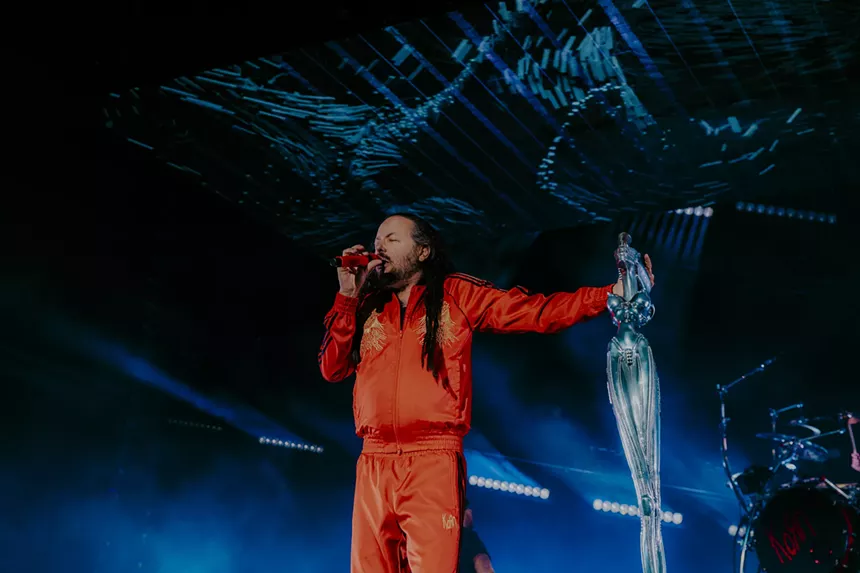 a man in a red jumpsuit behind a blue background.