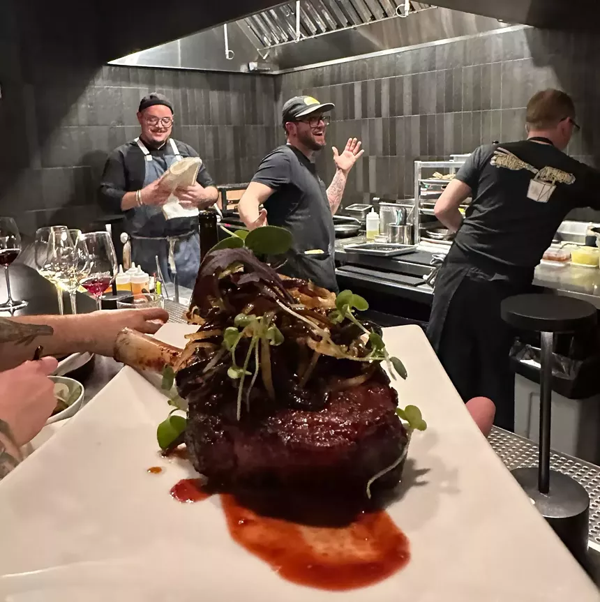 food on a plate with cooks in a kitchen behind it