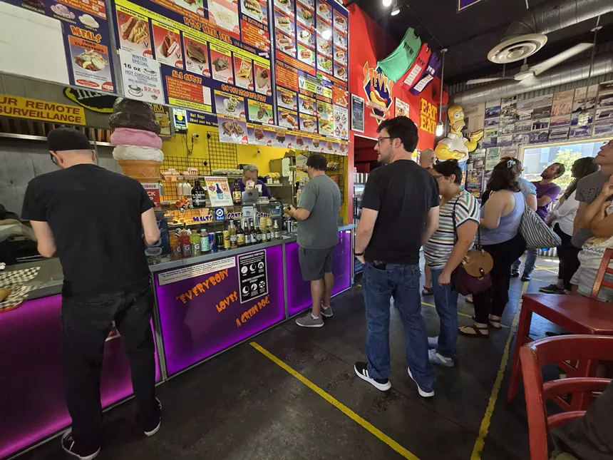 people standing in line at a hot dog coutner