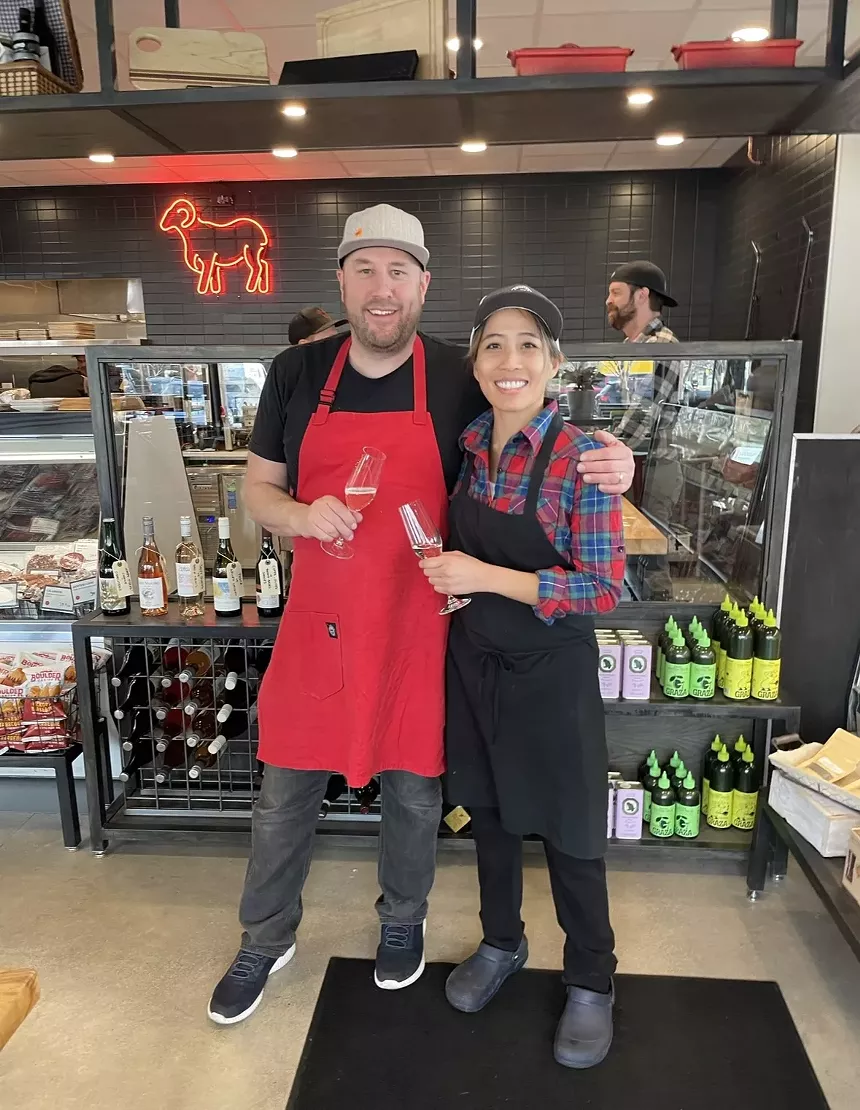 a man in a red apron posing with a woman in a black apron