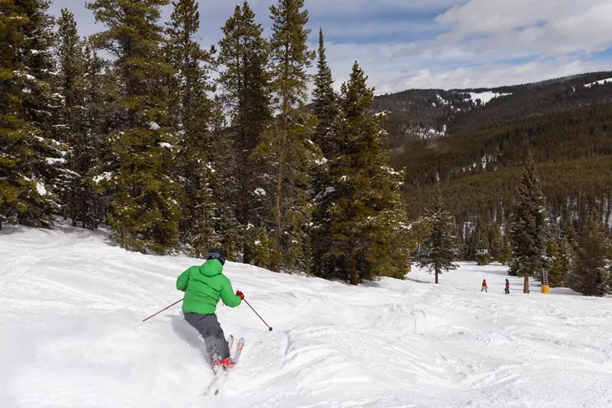 A person in a green coat skiing down a run at Ski Cooper